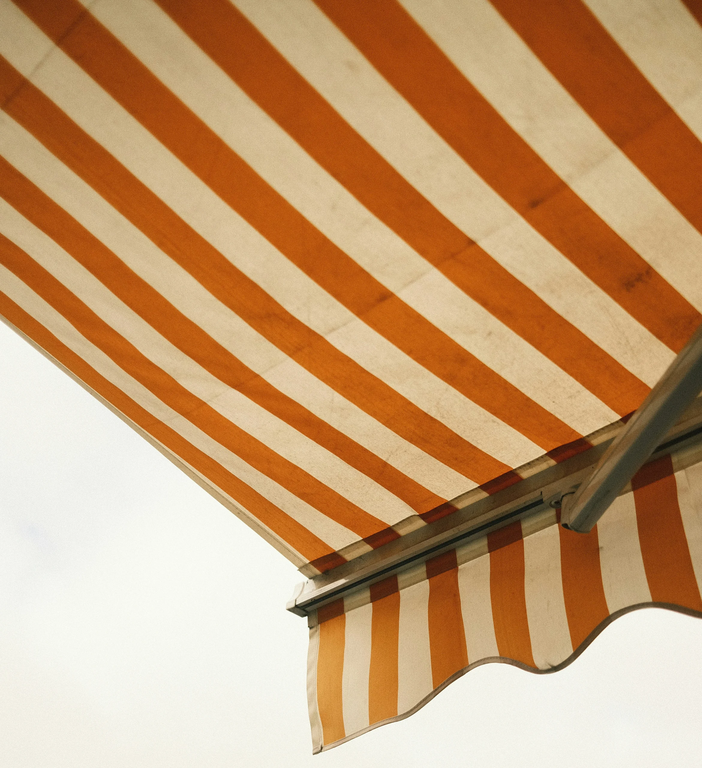 Foto de un toldo de color naranja y blanco, con todo de filtro sepia